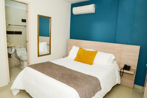 a bedroom with a large bed with a blue wall at Hotel Prado 34 West in Bucaramanga