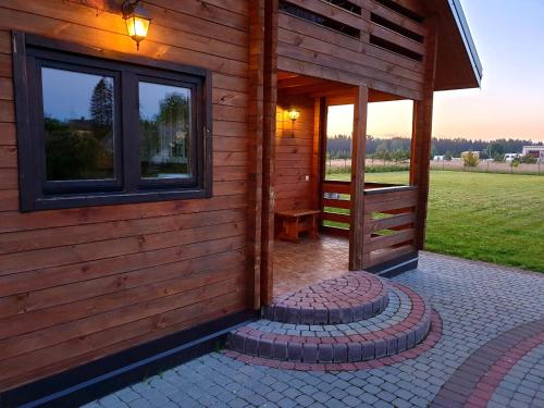 a wooden cabin with a window and a patio at Holiday House & Sauna in Druskininkai in Neravai