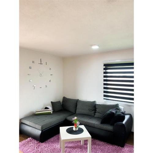 a living room with a couch and a clock on the wall at Modern Apartment in Brčko