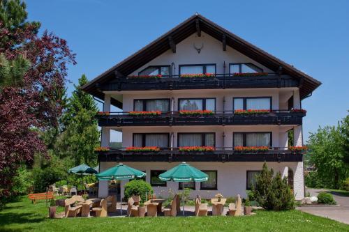a building with tables and umbrellas in front of it at Hotel Konradshof in Seewald