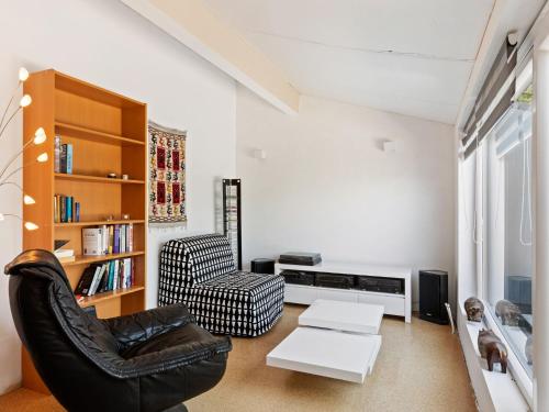 uma sala de estar com uma cadeira e uma estante de livros em Sun kissed Villa in Kobbegem with Private Garden 