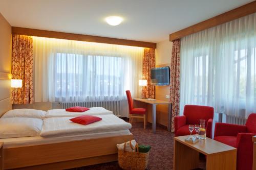 SeewaldにあるHotel Konradshofのベッド、テーブル、椅子が備わるホテルルームです。
