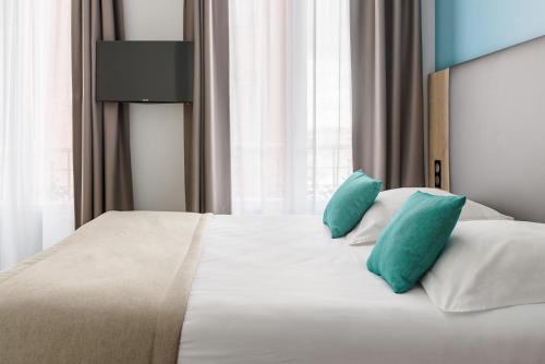 a bedroom with a large white bed with blue pillows at Grand Hôtel Clichy Paris in Clichy