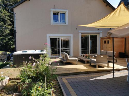a patio with chairs and a hot tub in front of a house at Le pavillon de l'herboriste 14p jacuzzi jardin in Tintigny
