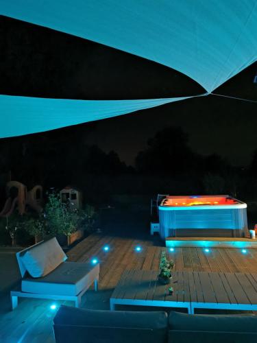 a deck with a bench and a bed under a tent at Le pavillon de l'herboriste 14p jacuzzi jardin in Tintigny