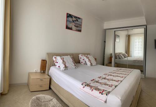 a bedroom with a large white bed with a mirror at Apartament Safir Mamaia in Mamaia