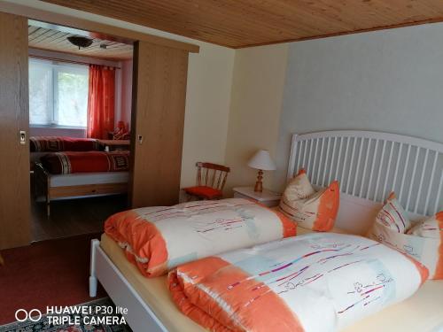 1 dormitorio con 2 camas y almohadas de color naranja y blanco en Fewo am Fuße der Bergbahn, en Mellenbach-Glasbach