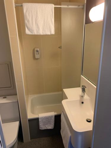 uma casa de banho com um lavatório, uma banheira e um WC. em Kyriad Direct Clermont Ferrand Nord Gerzat em Gerzat