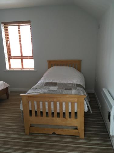 a bedroom with a wooden bed and a window at 4 Clifden Court in Clifden