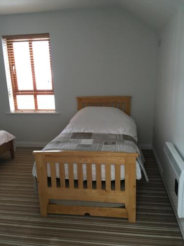 クリフデンにある4 Clifden Courtのベッドルーム1室(木製ベッド1台、窓付)