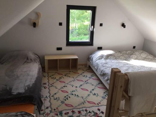 1 dormitorio en el ático con 2 camas y ventana en Marzeniec w Beskidzie Niskim en Wapienne