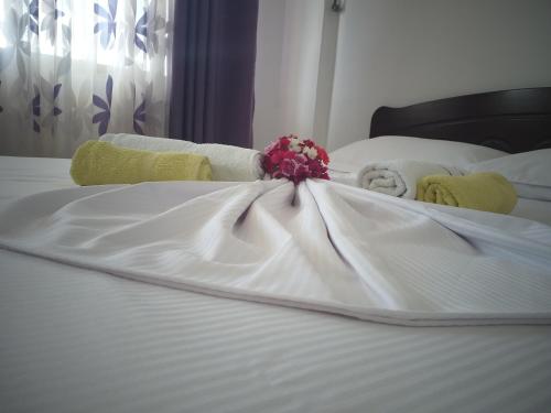 a white bed with towels and flowers on it at Grand Seaview Apartments in Ksamil
