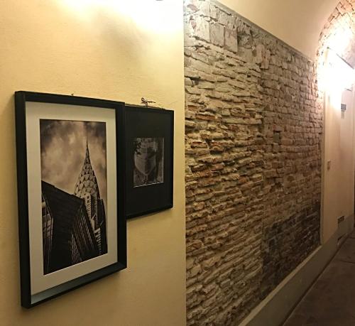 a wall with two pictures on a brick wall at Hostly - Garden House near the Tower - Historical house with Private Garden in Pisa