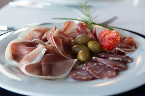a plate of food with meat and fruit on a table at Tenuta Su Vrau in Posada