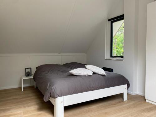 een wit bed in een witte kamer met een raam bij Vakantiehuisje Time Out in Zelhem