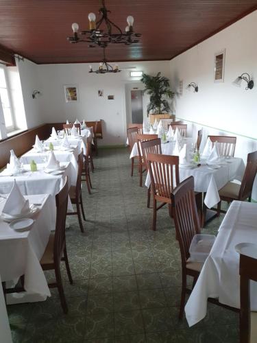 una sala da pranzo con tavoli bianchi e sedie in legno di Pension Waldhof am Stubenbergsee a Stubenberg