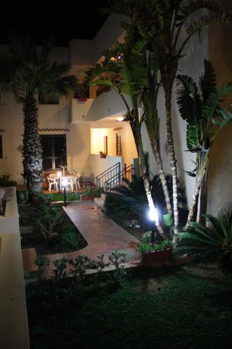 a courtyard with palm trees and a building at night at Residence Scirocco e Tramontana in Favignana