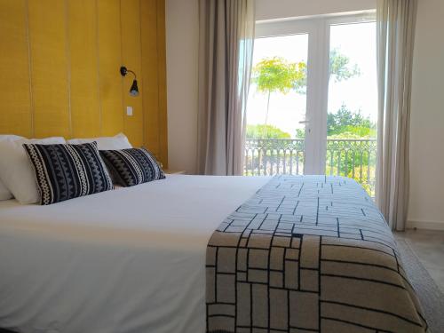 a bedroom with a large white bed with a window at Vila Louro in Santa Cruz