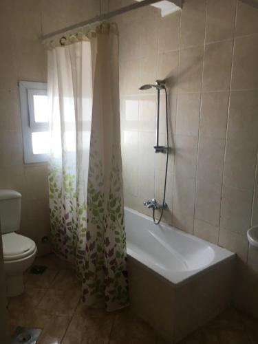 a bathroom with a tub and a toilet and a shower curtain at Luxury Villa Panorama Beach in El Alamein