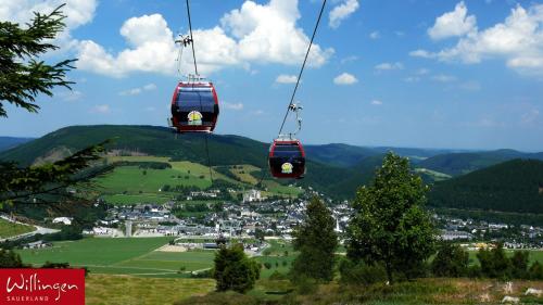 two cable cars are flying over a green valley at Göbels Landhotel in Willingen