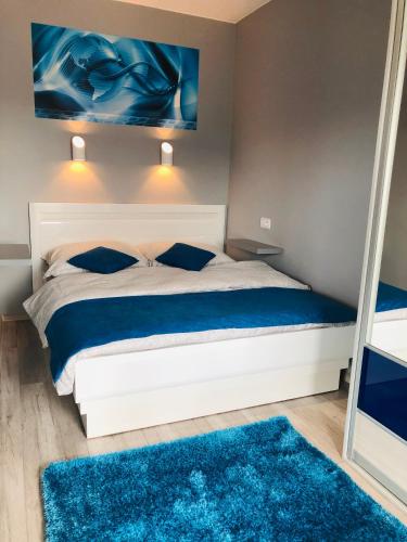 a bedroom with a bed with blue rugs and a mirror at GARDENIA BLUE APART Dziwnów z widokiem na morze in Dziwnów