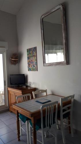 - une table à manger avec des chaises et un miroir dans l'établissement Les sardines, à Sète