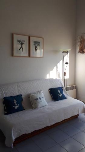 - un lit blanc avec des oreillers bleus dans l'établissement Les sardines, à Sète