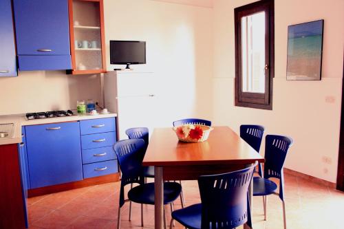 a kitchen with a wooden table and blue chairs at Residence Scirocco e Tramontana in Favignana