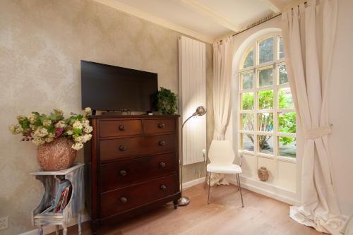 a room with a dresser with a television and a window at CASASdeCASPER - Studio Alkmaar in Alkmaar