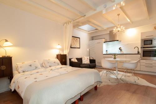 a white bedroom with a large bed and a kitchen at CASASdeCASPER - Alkmaar in Alkmaar