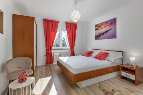 1 dormitorio con 1 cama con cortinas rojas y silla en Apartment IN, en Rijeka