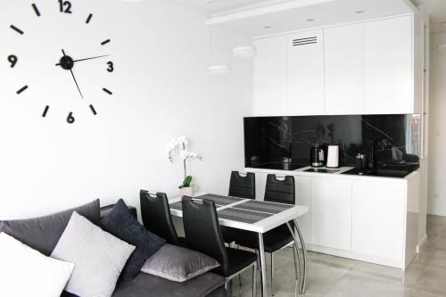 ein Esszimmer mit einem Tisch und einer Uhr an der Wand in der Unterkunft Apartament Wrocław Centrum Galeria Magnolia in Breslau