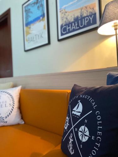 an orange couch with two pillows on it at Apartament Villa Baltic - Chalupy in Chałupy