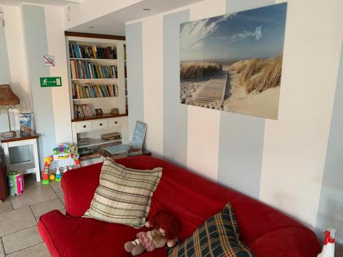 a red couch in a living room with a picture of a beach at Apartament Villa Baltic - Chalupy in Chałupy