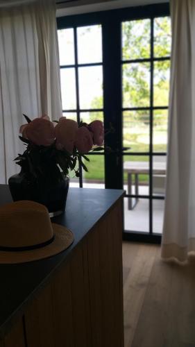 a vase of flowers on a counter with a hat at Muntershof in Velzeke-Ruddershove