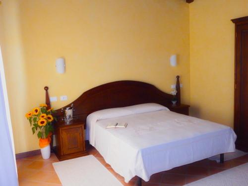 a bedroom with a bed and a vase of flowers at Tenuta Su Vrau in Posada