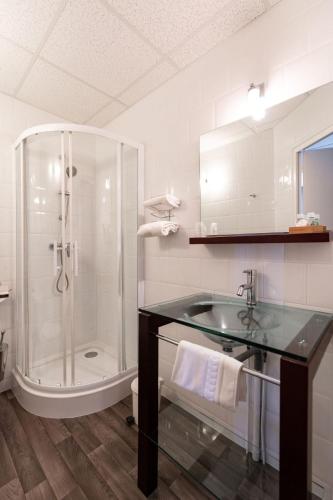 La salle de bains est pourvue d'un lavabo en verre et d'une douche. dans l'établissement Cit'Hotel Normandy Hotel Pornichet La Baule, à Pornichet
