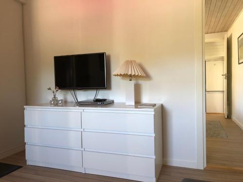 a television on top of a dresser with a lamp at Hyggelig ferielejlighed in Skagen