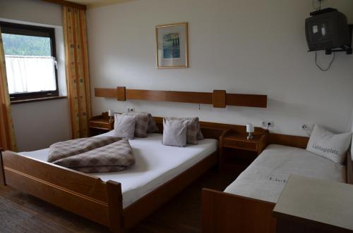 a bedroom with two beds and a tv on the wall at Gästehaus Wildauer in Schlitters