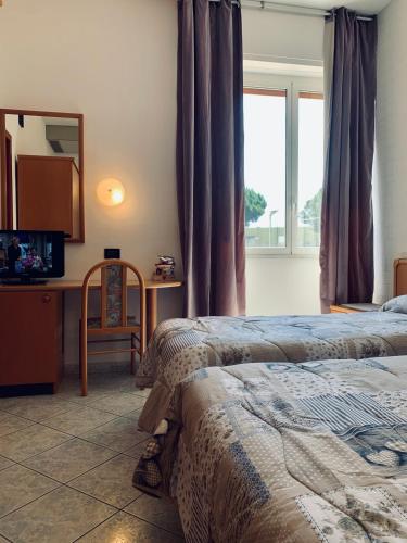 a bedroom with two beds and a desk and a window at Hotel San Giorgio in Albisola Superiore