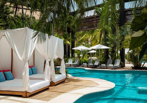 una piscina con 2 camas y sillas junto a una piscina en Vidanta Riviera Maya en Puerto Morelos
