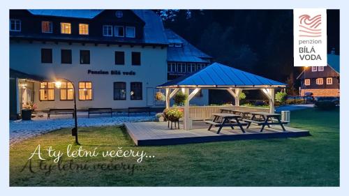 a picnic table and a gazebo in front of a building at Penzion Bílá voda in Harrachov