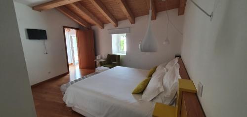 a bedroom with a white bed and a television at Casas de Campo da Barroca in Tabosa