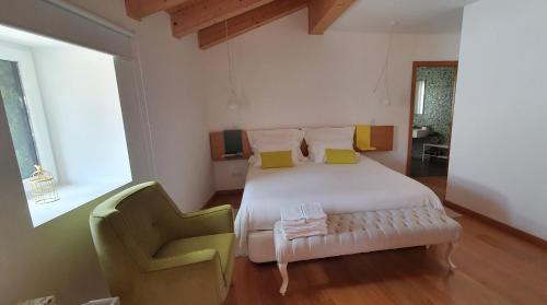 a bedroom with a white bed and a green chair at Casas de Campo da Barroca in Tabosa