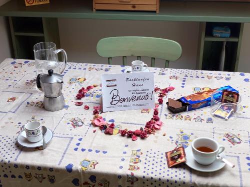 a table with a table cloth with a tea pot and a sign at Bachlaufen Haus in Sesto