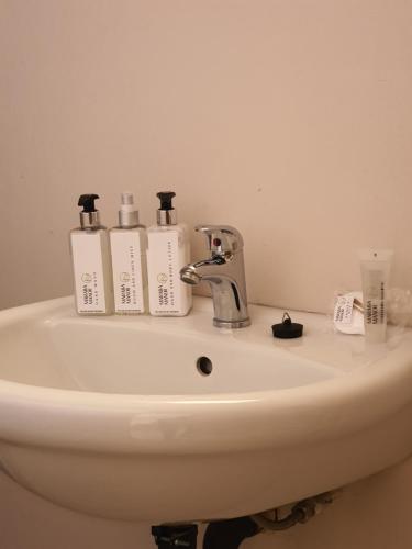 a bathroom sink with three bottles ofodorizers on it at Maraba Manor in Vryburg