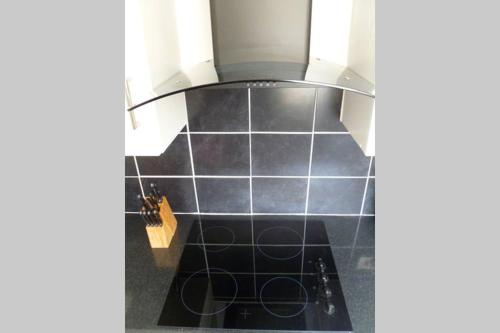 a kitchen with black tiles on the wall at Cosy and Peaceful Maisonette with Terrace, Kidderminster in Kidderminster