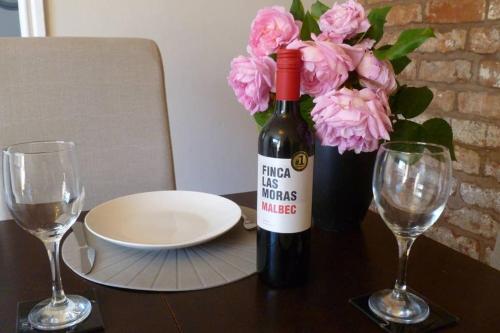 a bottle of wine sitting on a table with two glasses at Cosy and Peaceful Maisonette with Terrace, Kidderminster in Kidderminster