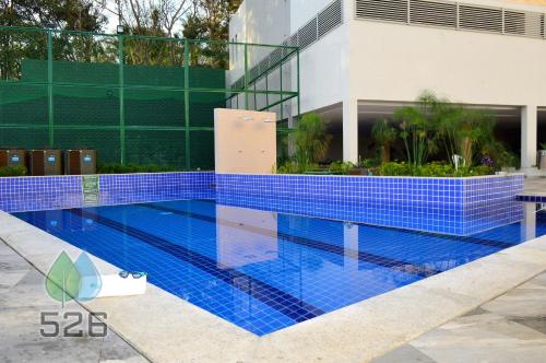 a swimming pool with blue tiles in front of a building at Park Veredas - Apto 526 - Flat Service in Rio Quente