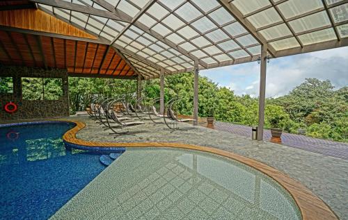 an outdoor swimming pool with chairs and a pergola at El Establo Mountain Hotel in Monteverde Costa Rica